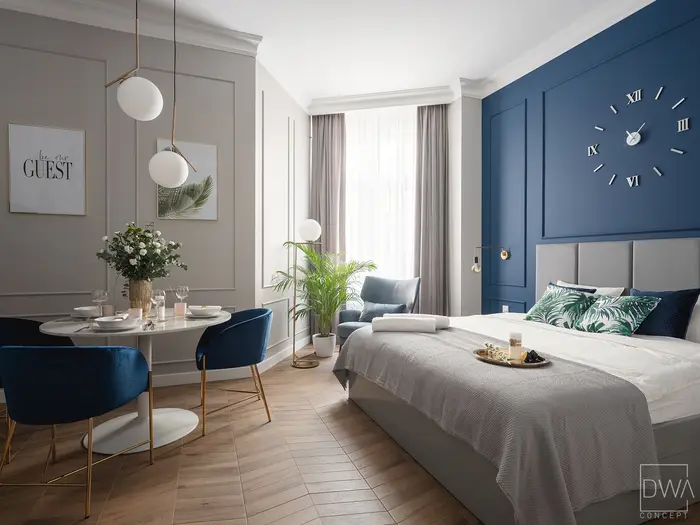 Sypialnia z granatową ścianą i okrągłym zegarem - apartament na Starym Mieście w Krakowie