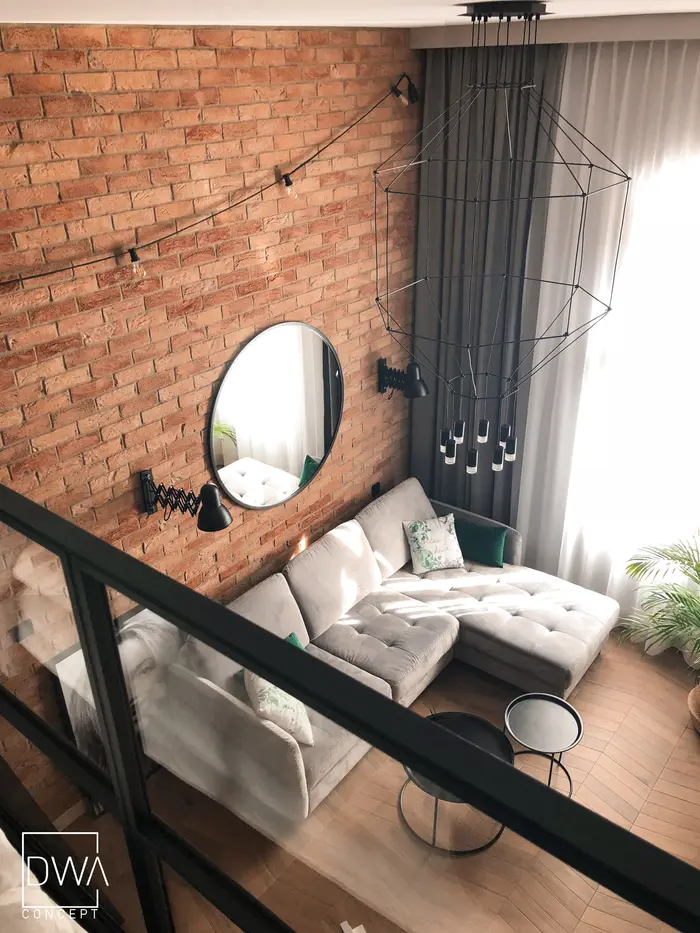 Loft z cegłą i okrągłym lustrem nad sofą - apartament w Krakowie 22 m2