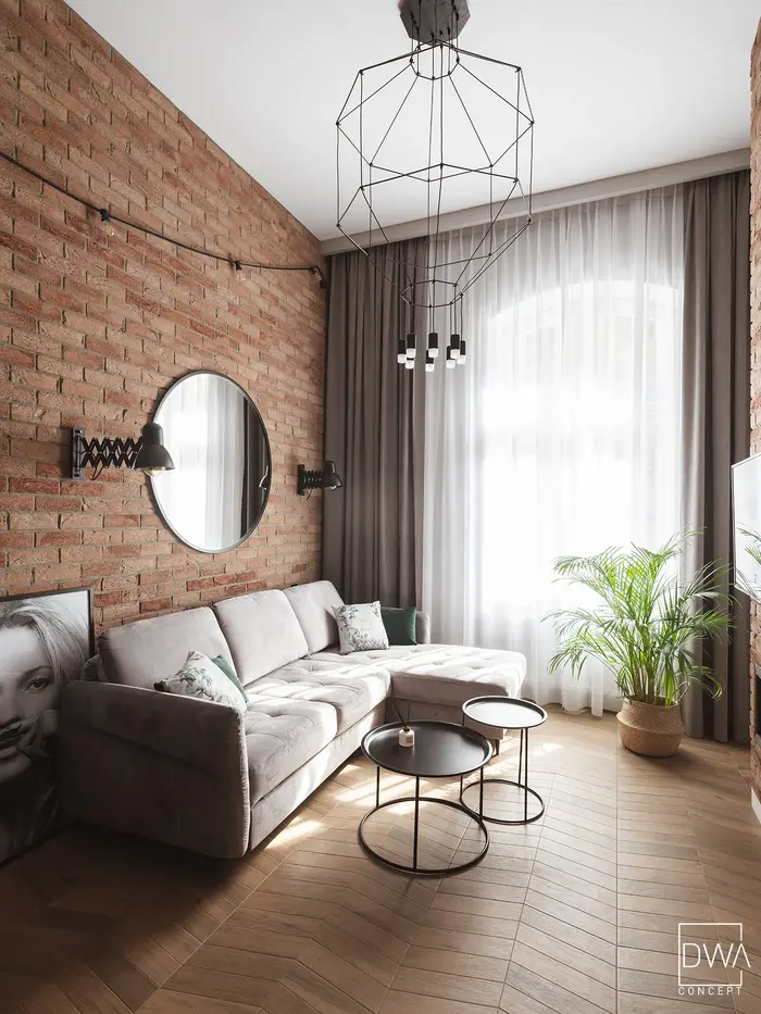 Salon z cegłą, czarnymi kinkietami i girlandą żarówek - apartament w Krakowie 22m2