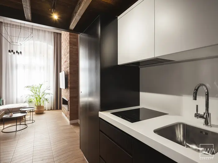 Czarno-biała zabudowa kuchenna z czarnym blatem i chromowaną baterią - apartament w Krakowie 22m2