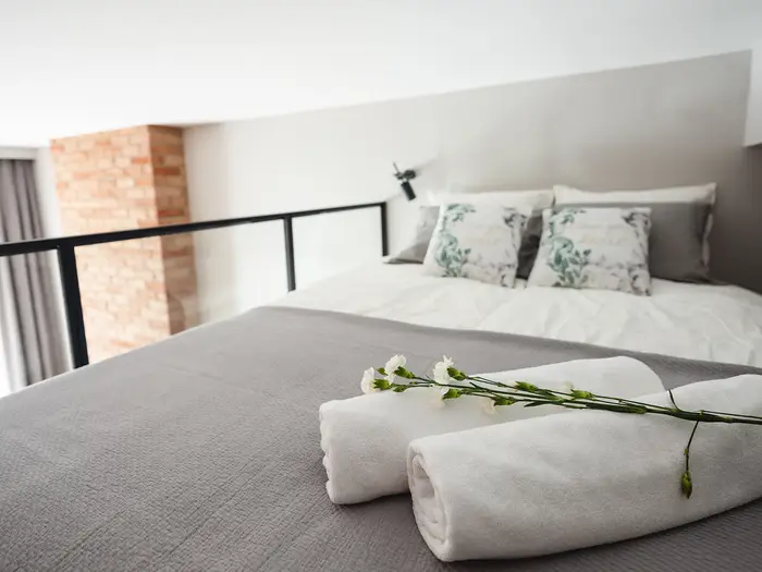 Antresola sypialniana z łóżkiem, ceglaną ścianą i szklaną balustradą - apartament w Krakowie 22m2