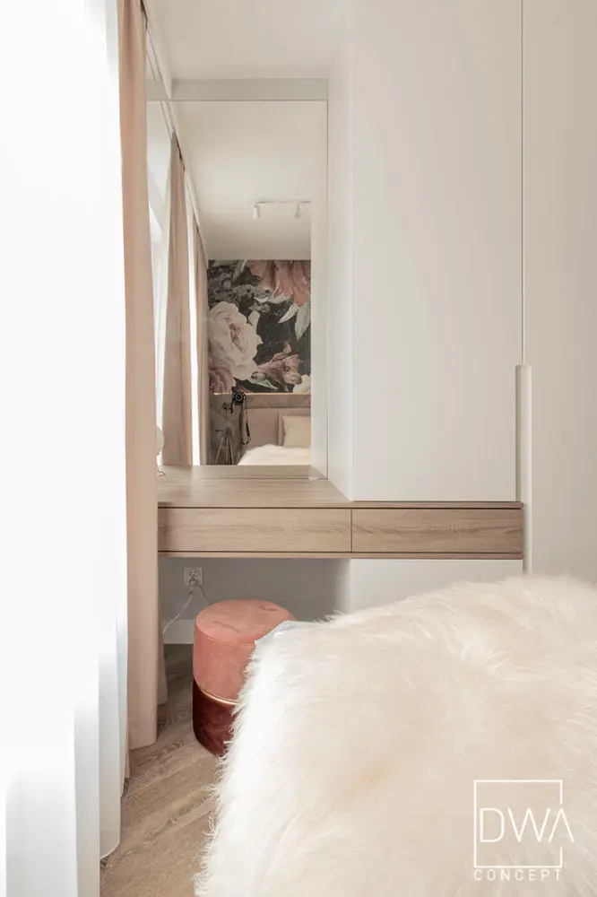 Toaletka z lustrem odbijającym kwiatową tapetę i bordową pufą - apartament 46m2 w Krakowie