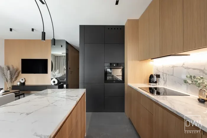 Kuchnia z czarną zabudową, piekarnikiem i marmurowym blatem - apartament w Krakowie