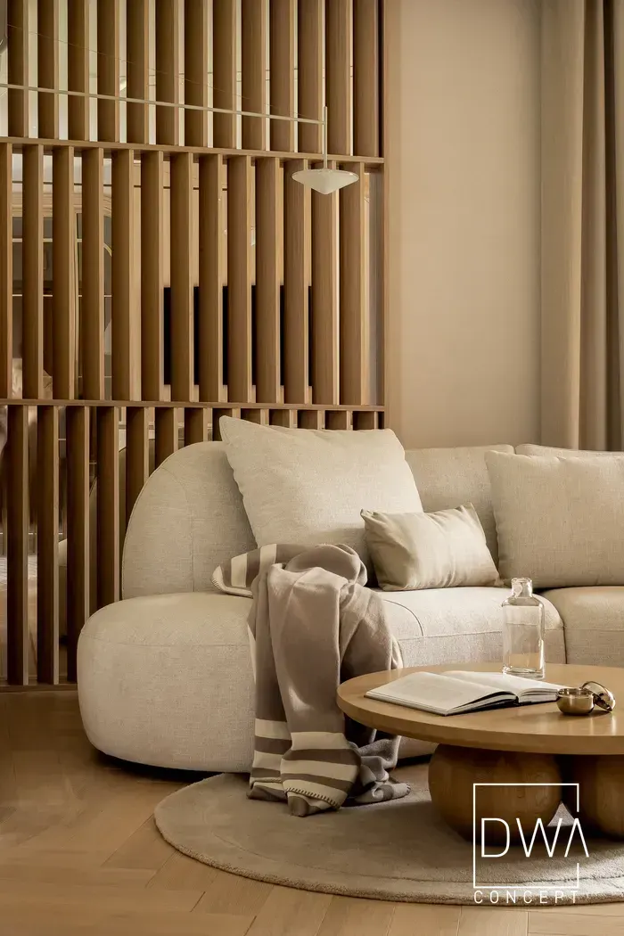 Sofa z poduszkami i pledem oraz drewnianą, ażurową przesłoną w salonie - apartament w Zakopanem